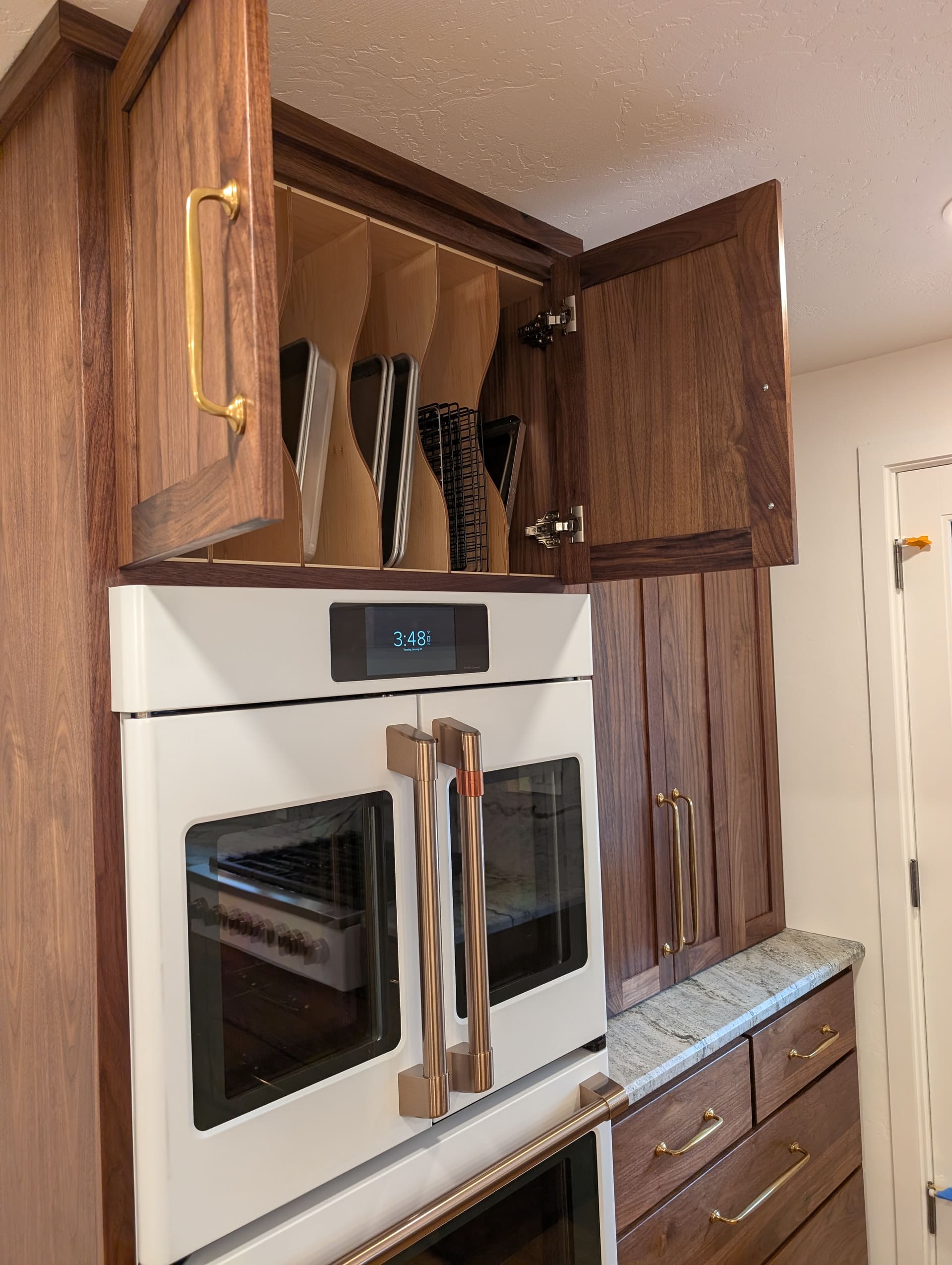Custom walnut floating shelves and built-in cabinetry in a dining nook with sage green accent wall
